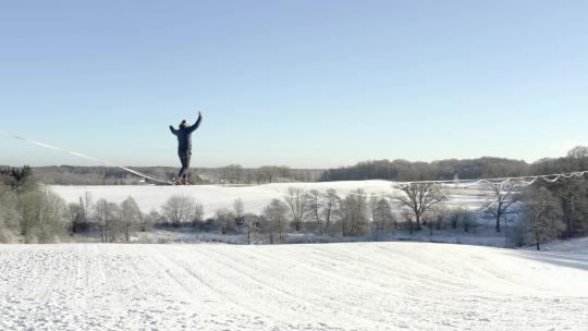 男子在白雪覆盖的田野上走钢丝视频素材模板下载