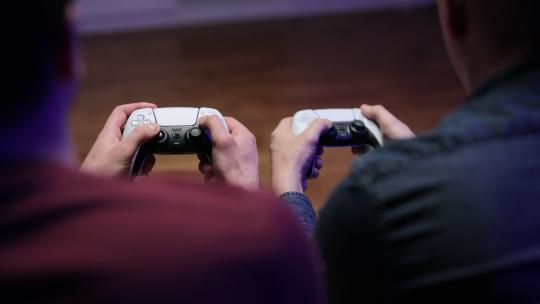 纽约——2021年3月7日：玩家双手使用操纵杆在控制台上玩足球足球模拟器视频游戏的特写镜头。索尼PlayStation 5电视游戏机的两个操纵杆
