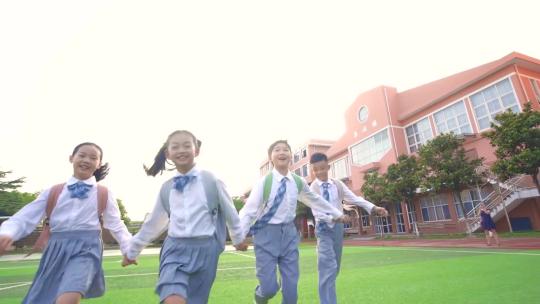 小学生们手拉手奔跑在学校操场里视频素材模板下载