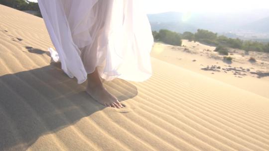 走在沙漠沙滩上的白裙女人