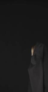 一个女人扔掉黑色套装露出她的白色无袖上衣竖屏