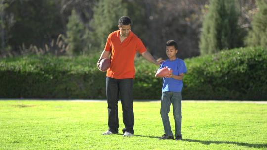 一位父亲教他的儿子如何踢球。视频素材模板下载