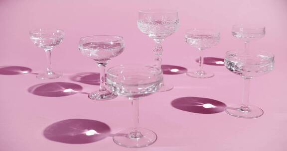 不同种类的水晶鸡尾酒杯在一个粉红色的表面
