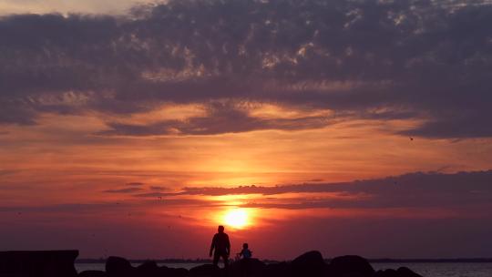 日落时分一对父子沿着海岸散步