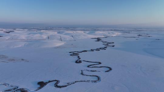 航拍雪原上蜿蜒的冰封河流暮色