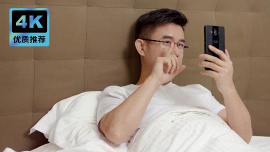 男子在床上视频通话使用手机男子居家玩手机