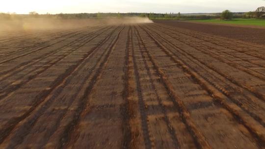 在尘土飞扬的田野鸟瞰图中用拖拉机和播种机播种田地视频素材模板下载