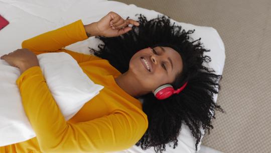 女人在床上戴着耳机听歌