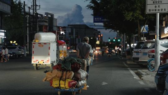 城市夜景一个生活老人在马路道路推着小推车