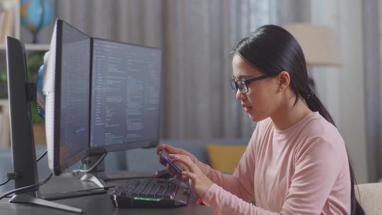 女孩程序员看着智能手机，然后在创建软件工程师开发应用程序时庆祝