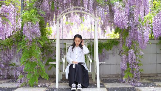 紫藤花海下坐摇椅看书的美少女孩飘落叶唯美