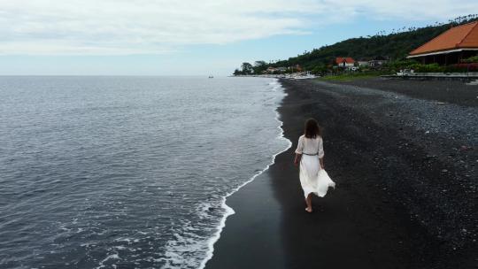 女人沿着黑沙滩散步