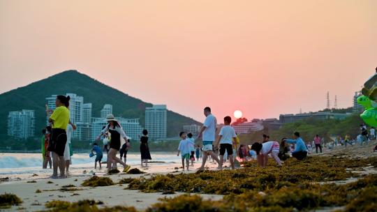 三亚大东海景区沐浴在夕阳余晖下的游客市民