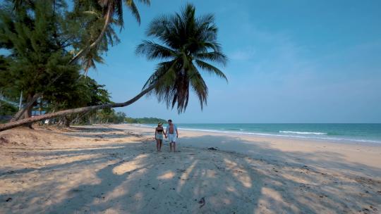 一对夫妇在热带海滩与棕榈树旁游玩