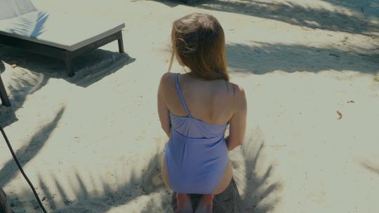 女人穿着泳衣坐在白色沙滩上视频素材模板下载