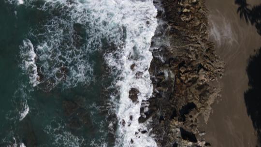 海浪在黑暗的沙滩上撞击岩石