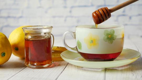在桌子上的一杯茶中倒蜂蜜