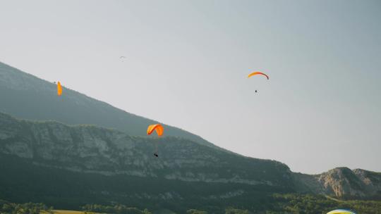 人们在山脉上空用滑翔伞飞行视频素材模板下载