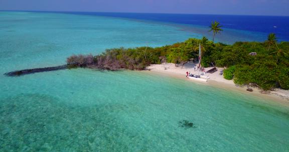 4K天堂阳光明媚的白色沙滩和蓝色大海背景的日间空中岛屿景观