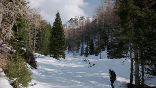 走在覆盖着厚厚的积雪的步道上。一个男人在斯洛文尼亚的卡拉万克阿尔卑斯山徒步旅行。
