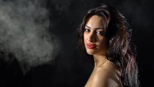 向摆姿势拍照的女模特喷烟雾