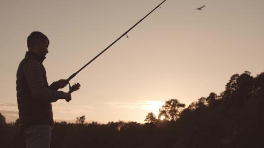 渔夫用旋转的鱼竿在河上捕鱼