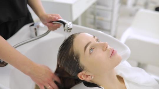 美容概念，理发师在美发沙龙洗头的年轻女子