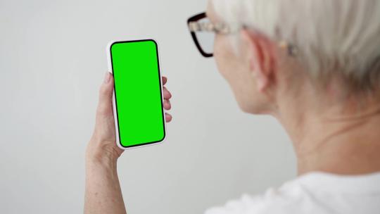 老人使用绿幕智能手机在视频通话