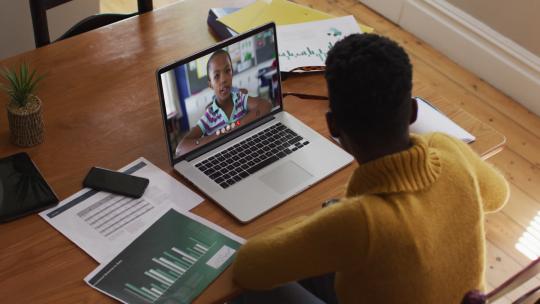 非裔美国女老师在家里用笔记本电脑视频通话时说话和做笔记视频素材模板下载
