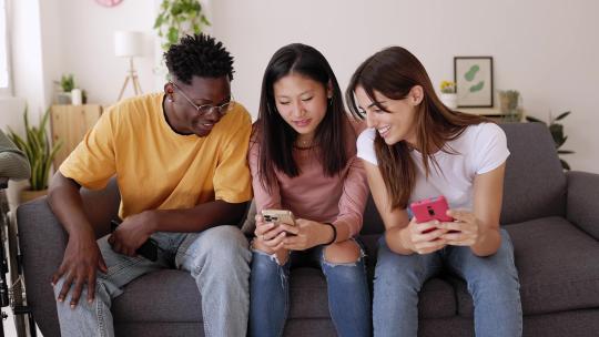 三个年轻人在沙发上玩手机视频素材模板下载