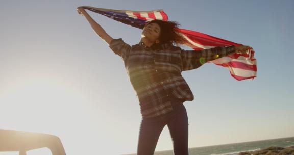海滩4k皮卡上挥舞美国国旗的女人