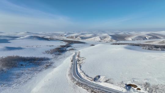 冬季丘陵山区蜿蜒穿行在雪野中的道路