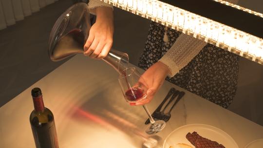 女人在餐厅灯光下倒红酒视频素材模板下载