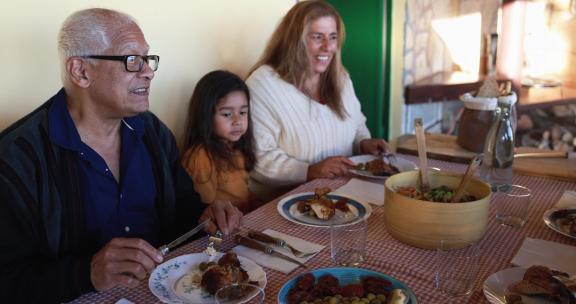 快乐的拉丁女孩在家和祖父母一起吃饭很开心