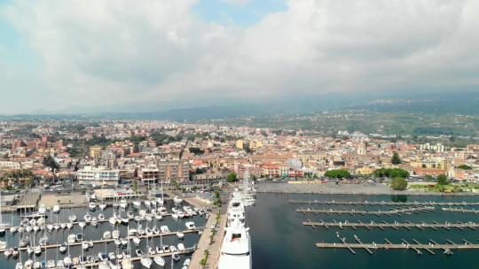 空中，空码头旁边满是船只的码头，沿海城镇，镜头广阔。里波斯托，西西里岛。