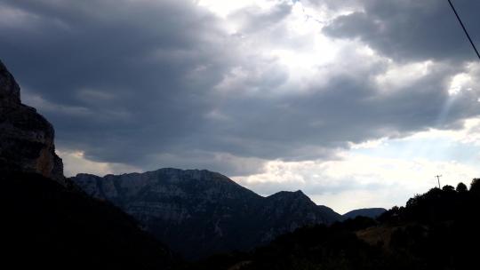 阳光穿过群山照射到Tymfi山脉上，广角镜头，延时拍摄。