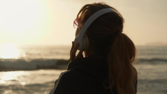 女人在沙滩上听音乐