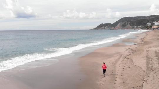 在海边的沙滩上跑步的女人视频素材模板下载