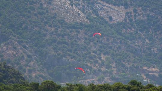 滑翔伞飞过森林覆盖的山脉