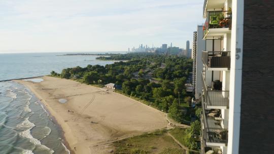 无人机靠近高层公寓，后面有海滩、湖岸大道和芝加哥天际线