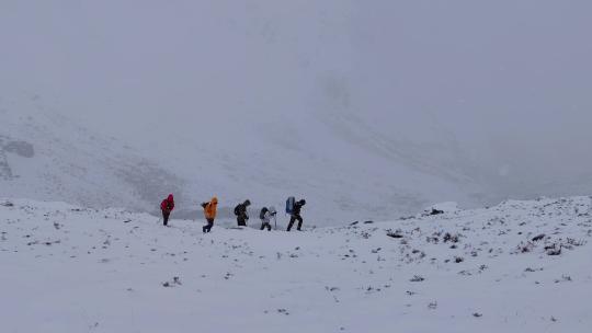 攀登岷山山脉都日峰的登山者在雪中徒步行进