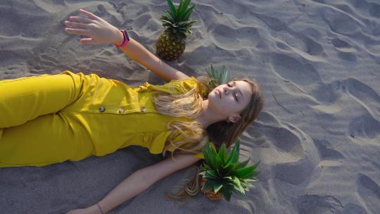 小女孩躺在菠萝中的沙滩上