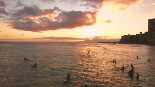 日落时分夏威夷海滩上的冲浪者 航拍