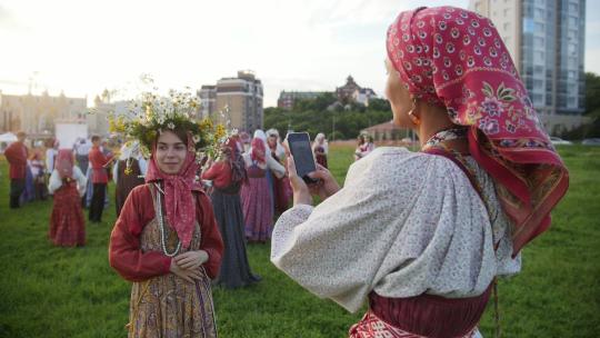 俄罗斯喀山，2017年7月19日，一名身着民族服装的女子正在拍摄俄罗斯民族音乐合奏