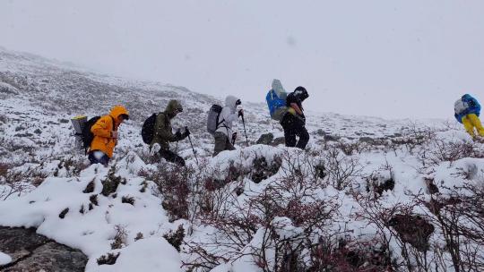 攀登岷山山脉都日峰的登山者在雪中徒步行进