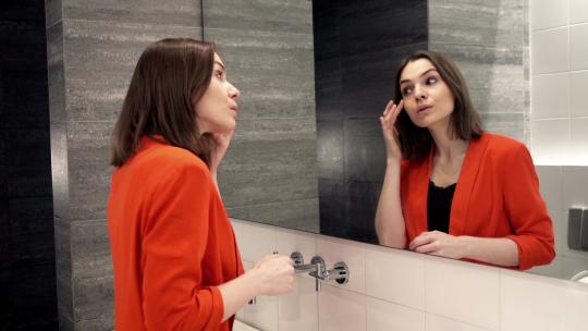 年轻漂亮的女人在浴室照镜子