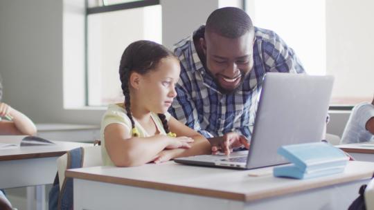快乐的非裔美国男老师用笔记本电脑帮助高加索女孩的视频
