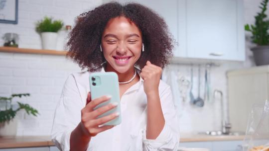 年轻的非裔美国妇女在自己的厨房里用手机打视频电话