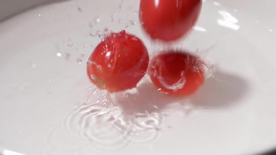 小西红柿掉进装有水的容器中的慢镜头