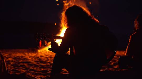 一个男人在海滩篝火上弹吉他